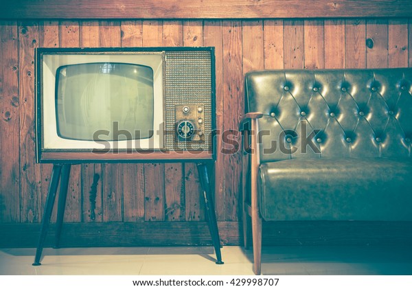 Retro\
television and vintage sofa with vintage wooden background. Classic\
vintage style home decoration. Retro style\
concept.