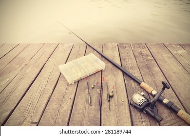 Retro toned picture of fishing equipment on wooden pier.