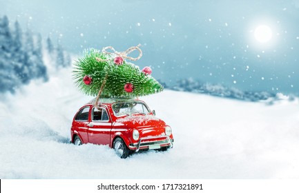 Retro toy car carrying christmas tree on roof in snowy winter forest. Christmas background. Holidays card. - Powered by Shutterstock