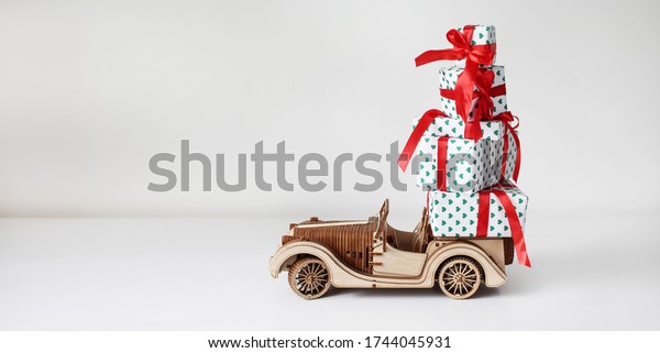 Retro toy car delivering gifts box for\
holidays on white\
background.