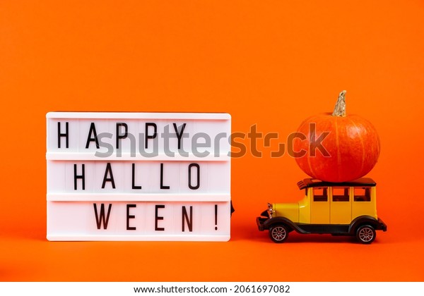 Retro toy car\
with a pumpkin on an orange background. Halloween and autumn\
harvest concept, place for\
text.