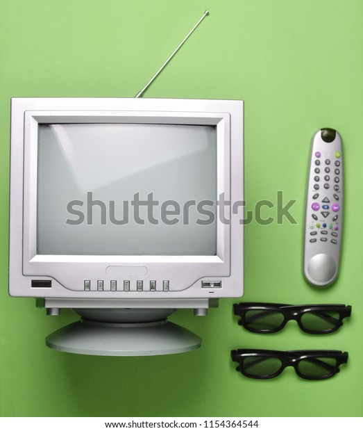 Retro tube TV, 3d\
glasses and remote control on green background. Top view, vintage\
video technology\
