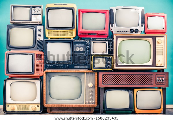 Retro TV receivers set from circa 60s, 70s and 80s\
of XX century, old wooden television stand with amplifier front\
mint blue wall background. Broadcasting, news concept. Vintage\
style filtered photo