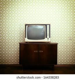 Retro tv with wooden case in room with vintage wallpaper and parquet, toned