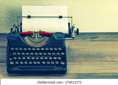 Retro Typewriter With White Paper Page On Wooden Table. Vintage Style Toned Picture