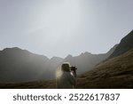 Retro video camera, traveler in Scottish nature. A traveler holding retro video camera taking video of Scottish nature. A traveler with retro camera is taking a video of a Scottish nature landscape.