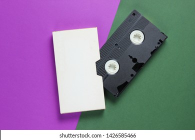 Retro video cassette with cover on color paper background. Top view