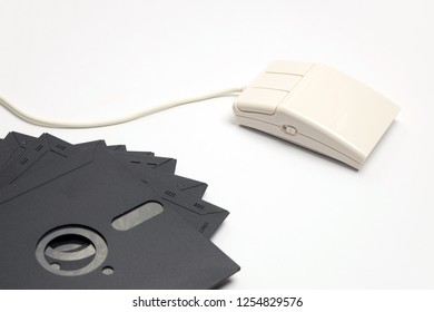 Retro White Three-button Computer Mouse With Five-inch Floppy Disks For Storing Information On A White Background. Image Of Outdated Computer Technology And Devices.