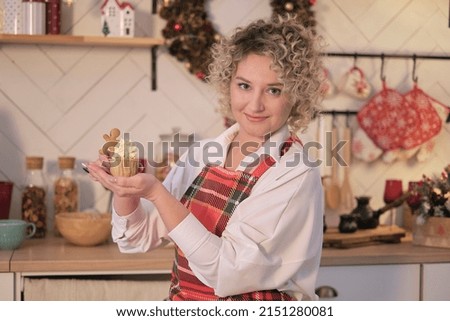 Retro woman female. housewife wearing colorful red apron holding tray with home cooked cupcakes standing in the kitchen. Housework concept