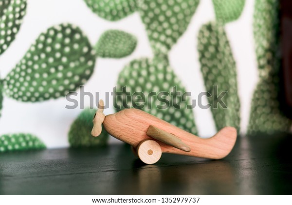 retro wood toy airplane on table with green\
cactus background.