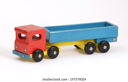 Retro Wooden Toy Truck In A Simple Rustic Design Painted In Red, Blue And Yellow With An Open Flatbed, Wheels And An Articulated Front Cab On A White Background