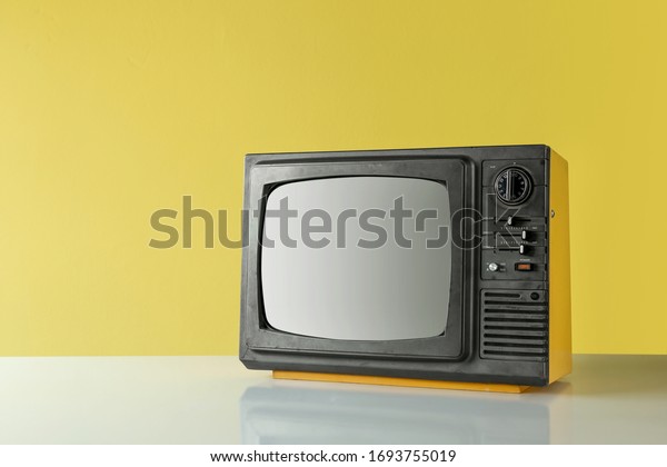 Retro\
yellow old TV on table with yellow wall\
background