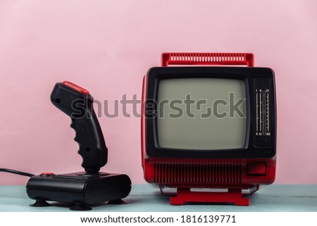 Retrogaming. Video game competition. Old TV with joystick on pink background. Attributes 80s