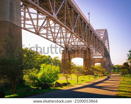 Retro-style old bridge skeleton structures and afternoon sun shadows over the windy park. Springtime Cape Cod Canal landscape under Bourne Bridge.
