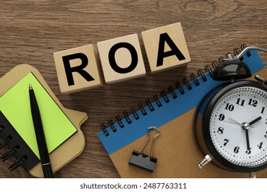 Return On Assets. ROA table clock and wooden cubes on the work table. text on wooden blocks