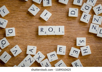 Return On Investment, ROI, Performance Measure Of Business Efficiency, Target And Goal, Cube Wooden Block With Alphabet Building The Word ROI On Grid Line Paper, R