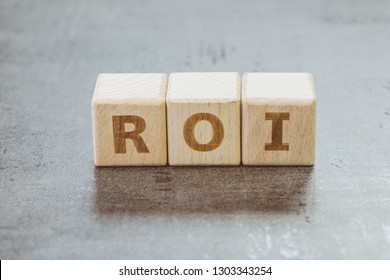 Return On Investment, ROI, Performance Measure Of Business Or Investment Efficiency, Target And Goal, Cube Wooden Block Building The Word ROI On Chalkboard.