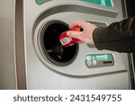 Returning empty bottles and cans in the recycling machine at the supermarket to reduce waste and reuse plastic, glass and aluminum. Hand holding a cola can in front of the machine.