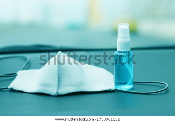 Reusable cloth mask and alcohol based hand\
sanitizer spray placed on car console.Concept about new\
normal,social distancing,business, \
 and travel guideline for\
prevention of Covid-19\
(Coronavirus).
