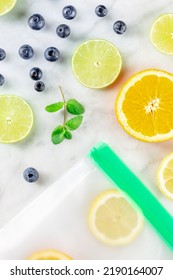 Reusable Food Storage Bags With Fresh Fruit, Top Shot On A White Marble Background. Citrus Slices In Ziplock Containers