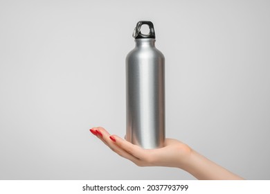 Reusable iron water bottle in a woman's hand, red nail polish