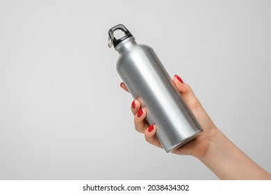 Reusable iron water bottle in a woman's hand, red nail polish