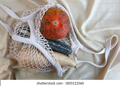 Reusable macrame bag with three different gourds. Top view, beige fabric background.