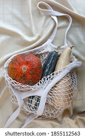 Reusable macrame bag with three different gourds. Top view, beige fabric background.