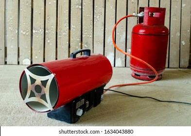 Reusable Orange Tank With Liquefied Oil Or Liquefied Petroleum Gas (CIS) Used For Household Needs (cooking, Central Heating, Water Heating). Selective Focus. Red Gas Air Heater And Gas Cylinder