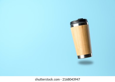 A reusable thermos cup for drinks flies in the air on a pastel blue background. Concept of plastic-free and zero waste living. Sustainable lifestyle. Personal takeaway beverages cup. - Shutterstock ID 2168043947