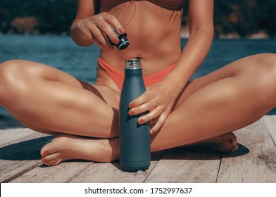 Reusable water thermo bottle in hands of fit young woman outdoors.No plastic use, zero waste ideology - Shutterstock ID 1752997637