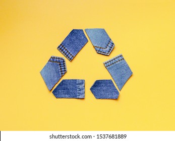 Reuse, reduce, recycle concept background. Recycle symbol made from old jeans on yellow background. Top view or flat lay.