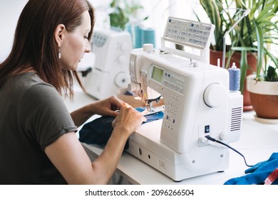 Reuse, Repair, Upcycle. Denim Upcycling Ideas, Repair And Using Old Jeans. Close-up Of Sewing Machine With Shabby, Old, Torn Denim Jeans Fabric. Sewing Studio Working Process.