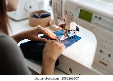 Reuse, Repair, Upcycle. Denim Upcycling Ideas, Repair And Using Old Jeans. Close-up Of Sewing Machine With Shabby, Old, Torn Denim Jeans Fabric. Sewing Studio Working Process.