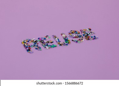 Reuse Text Consisting Of Small Recycled Plastic Pellets Collected From The Sea Water. Rethinking The Environment By Reducing Or Reusing Plastics. Circular Economy Concept. Lilac Purple Background