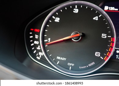 Rev counter of car selective focus closeup with copyspace.Tachometer or revolution counter, RPM gauge with red glowing needle on car dashboard with fuel and engine temperature indicators.