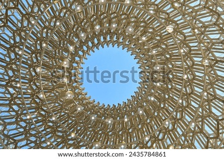 A reverse birds eye view shot of a an architectural art piece built to resemble a beehive. The structure is an example of biomimicry, demonstrating the ingenious nature of bees. 