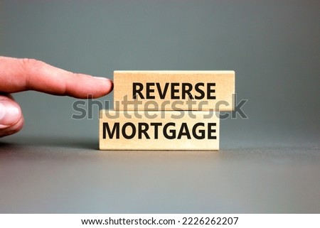 Reverse mortgage symbol. Concept words Reverse mortgage on wooden blocks. Beautiful grey table grey background. Businessman hand. Business and reverse mortgage concept. Copy space.