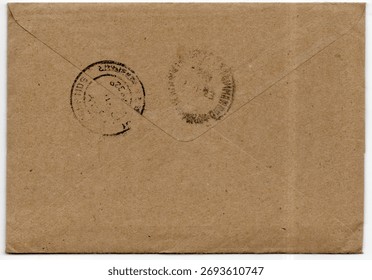 Reverse side of brown envelope showing two faded cancellations isolated on a white background. No visible postage stamp or address. Flap sealed.
