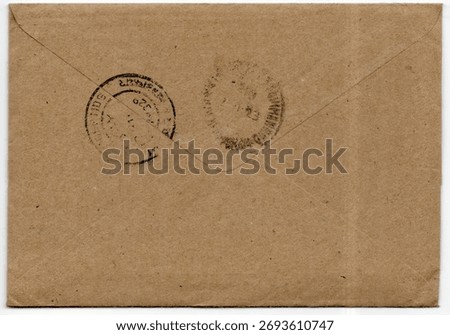 Reverse side of brown envelope showing two faded cancellations isolated on a white background. No visible postage stamp or address. Flap sealed.