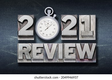 review 2021 phrase made from metallic letterpress with vintage stopwatch on dark jeans background