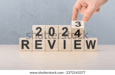 Review 2024. hand flips wooden cube and changes words REVIEW 2023 to REVIEW 2024. New year 2024. Economy and business. Phrase 2024 review on wooden table