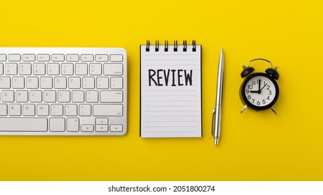 Review and assessment concept with computer keyboard and notebook on yellow background, top view