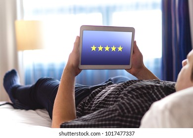 Review And Five Star Rating With Mobile Application. Customer Satisfaction Survey And Feedback App On Tablet. Man Using Modern Smart Device In Home Bedroom Or Hotel Room.