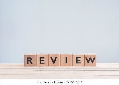 Review headline sign made of wood on a table