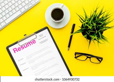 Review resumes of applicants. Resume on yellow work desk with coffee, glasses, keyboard top view - Shutterstock ID 1064930732