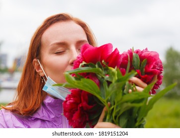 Revival After Coronavirus. Redhead Girl Sniffs Pink Flowers With Pulled Down Medicine Mask. Recovery After Covid And Flu. Sense Of Smell Return. 
