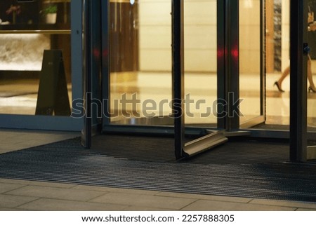 Revolving door of modern office building in night. Woman goes inside. Long business day. Occupation theme. Low angle view