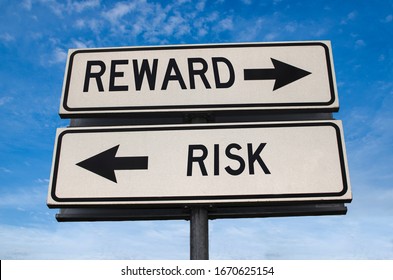 Reward Vs Risk. White Two Street Signs With Arrow On Metal Pole With Word. Directional Road. Crossroads Road Sign, Two Arrow. Blue Sky Background. Two Way Road Sign With Text.