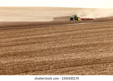 Rexburg, Idaho, USA  April 11, 2012  A farmer drives a tractor pulling a planter and fertilizer spreader, planting wheat in the fertile farm fields of Idaho.